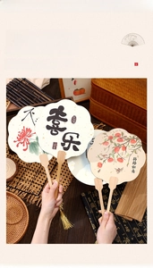 Detail of Chinese vintage hand fan featuring traditional calligraphy and golden silk tassel