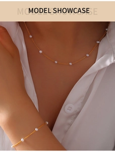 Close-up of gold-plated titanium necklace and bracelet set with delicate white pearls