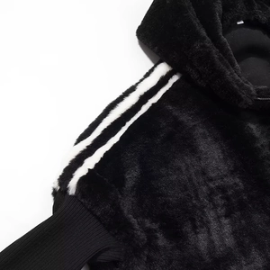 Detail of black faux fur jacket showing shoulder texture and white sleeve stripes