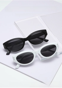 Flat lay of cat eye sunglasses in black and white with metal rivet details