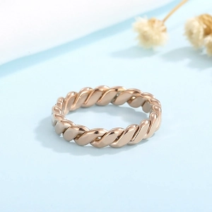 Macro shot of rose gold braided twist ring on blue background with dried flowers