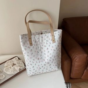 Détail du sac cabas en toile à fleurs roses avec anses en cuir marron élégantes