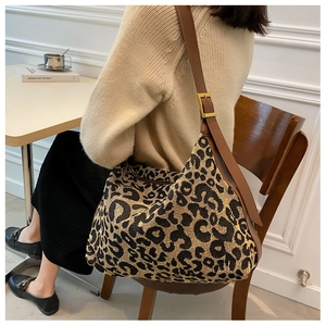 Close-up of leopard print shoulder bag with brown leather strap and gold buckle detail