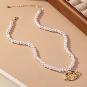 Elegant pearl necklace with gold Saturn planet pendant and blue gemstone accents