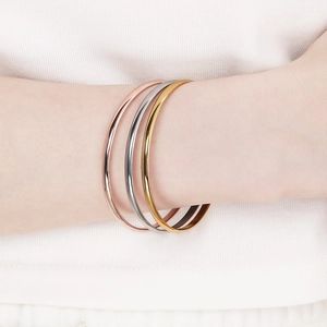 Close-up of minimalist gold silver and rose gold stackable stainless steel bangles set