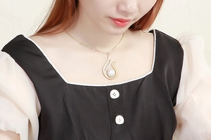 Detail of elegant gold swan pendant with pearl and rhinestones on a female model