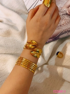 Detail showing 18k gold plated titanium steel bangle and stacked wavy rings on model