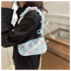 Detail of light blue floral shoulder bag featuring pink roses and ruched cloud strap