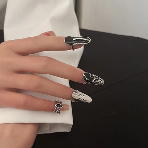 Detail of gothic silver nail ring set with black star patterns and fluid punk textures