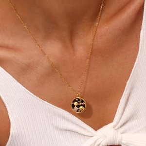 Detail of gold coin necklace with celestial moon and star charms on a model neck