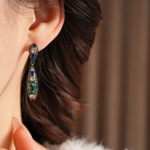 Détail de boucles d'oreilles vintage avec zircons colorés portées par un mannequin