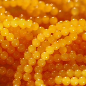 Macro shot of 8mm bright orange round glass beads with a glossy polished finish