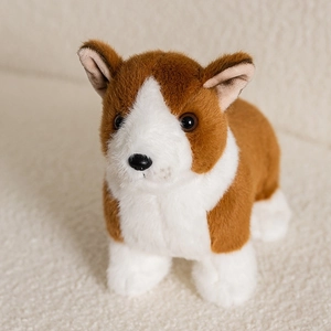 Close-up of soft plush Corgi puppy toy sitting on a warm cream textured blanket