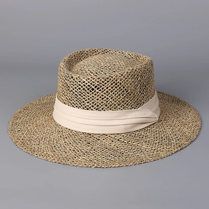 Detailed close-up of the woven texture and cream ribbon on this wide brim straw sun hat