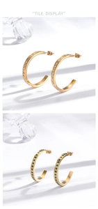 Detail of C-shaped gold-plated stainless steel earrings with white and green crystals