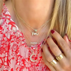 Detail of layered gold necklaces with crescent moon, star, and mama letter pendants