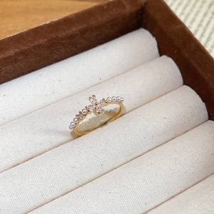Macro shot of gold zircon flower ring with micro pearls in a luxury jewelry box