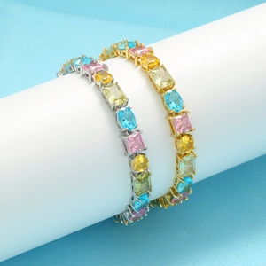 Colorful zircon prong-set jewelry set with gold and silver bracelets on white pedestals