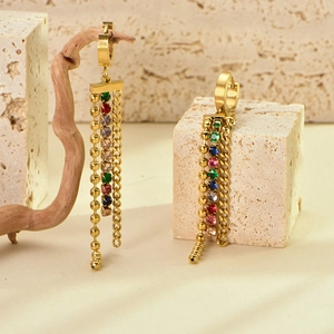 Close-up of long tassel earrings with colorful zircons on a rustic stone background
