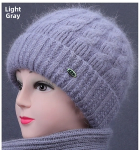 Detail of light purple knit hat and scarf set with metal tag on textured fabric