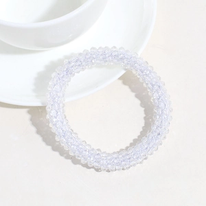 Close-up of sparkling clear rhinestone beaded hair tie next to a white teacup
