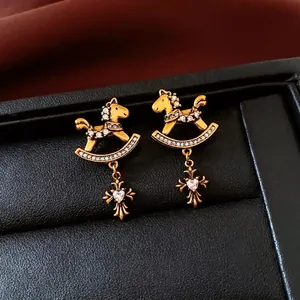 Vintage gold rocking horse earrings with zircon cross pendants on black leather