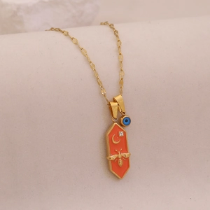 Detail shot of golden hexagon bee pendant with orange enamel and blue evil eye charm