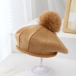 Détail du béret en maille kaki avec texture épaisse et pompon duveteux assorti au sommet