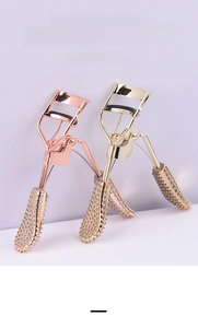 Detail view of rose gold eyelash curlers with non-slip beaded handle texture and spring