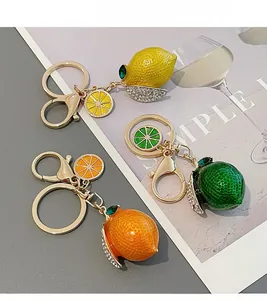 Close-up of three sparkling fruit keychains with rhinestones and golden hardware