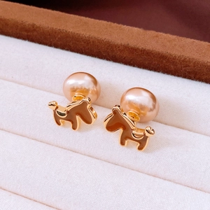 Macro shot of gold dog stud earrings with champagne pearls on white velvet box
