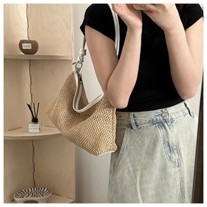 Detail of handwoven straw tote bag with white leather knotted shoulder strap detail