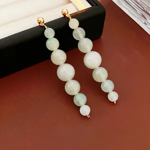 Elegant gold drop earrings with six gradient green aventurine beads on a dark leather base