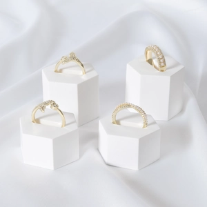 Minimalist gold rings with pearls and zircons on white hexagonal geometric displays