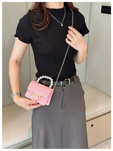 Close-up of pink jelly bag with pearl handle and quilted pattern on a fashion model