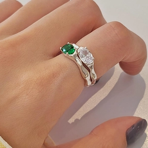Detail of silver rings with green and white zircons and irregular lava texture