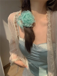 Detail of light green silk flower hair claw clip worn on model for a soft vacation look
