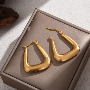 Minimalist brushed gold geometric earrings on elegant dark brown jewelry display stand
