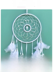 Detail of handcrafted white dream catcher featuring mesh weaving and soft feathers