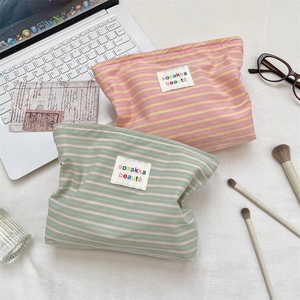 Flat lay of striped macaron colored makeup bags with brand labels on a desk