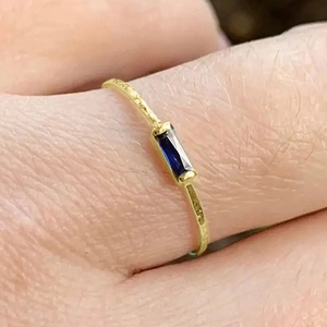 Macro shot of minimalist gold thin ring with rectangular deep blue sapphire gemstone