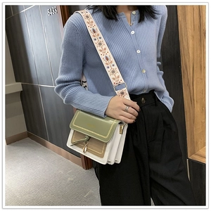 Detail of color-block crossbody bag with ethnic patterned strap and tassel accent