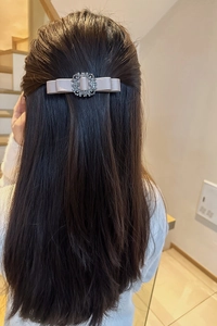 Close-up detail of the elegant fabric bow hair clip featuring sparkling rhinestones centerpiece.