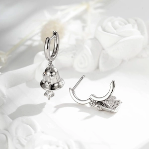Minimalist silver bell earrings with star motif and clear gemstone on a branch