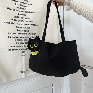 Detail of cute black cat-shaped canvas tote bag with yellow eye and collar embroidery