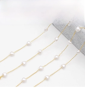 Macro detail of golden metal chain necklace with glossy heart-shaped white pearls