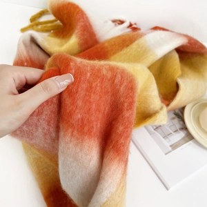 Close-up of soft mohair texture on orange and yellow plaid scarf with a cozy feel