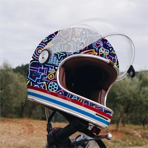 Detail of retro motorcycle helmet with neon geometric graphics on handle with forest backdrop