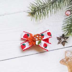 Detail of Christmas bow hair clip with strawberry pattern and mushroom leaf charms