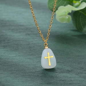 Macro shot of gold teardrop stone pendant with a cross on a gold chain necklace